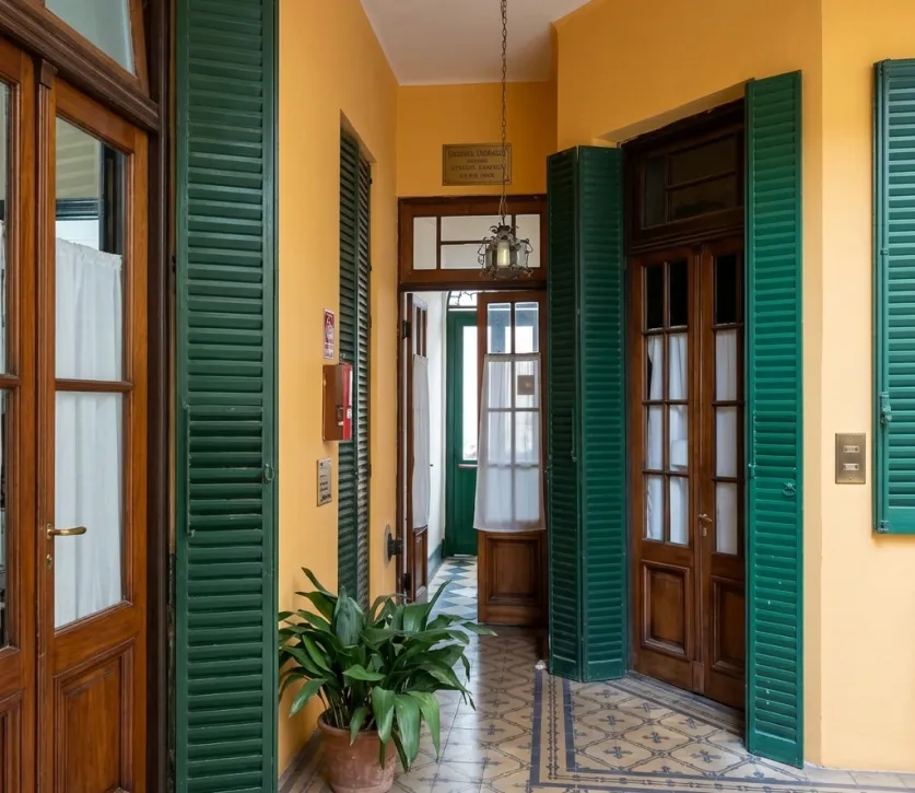 Galería interior de la sede Lanús de Ananké, con persianas verdes y piso de mosaicos