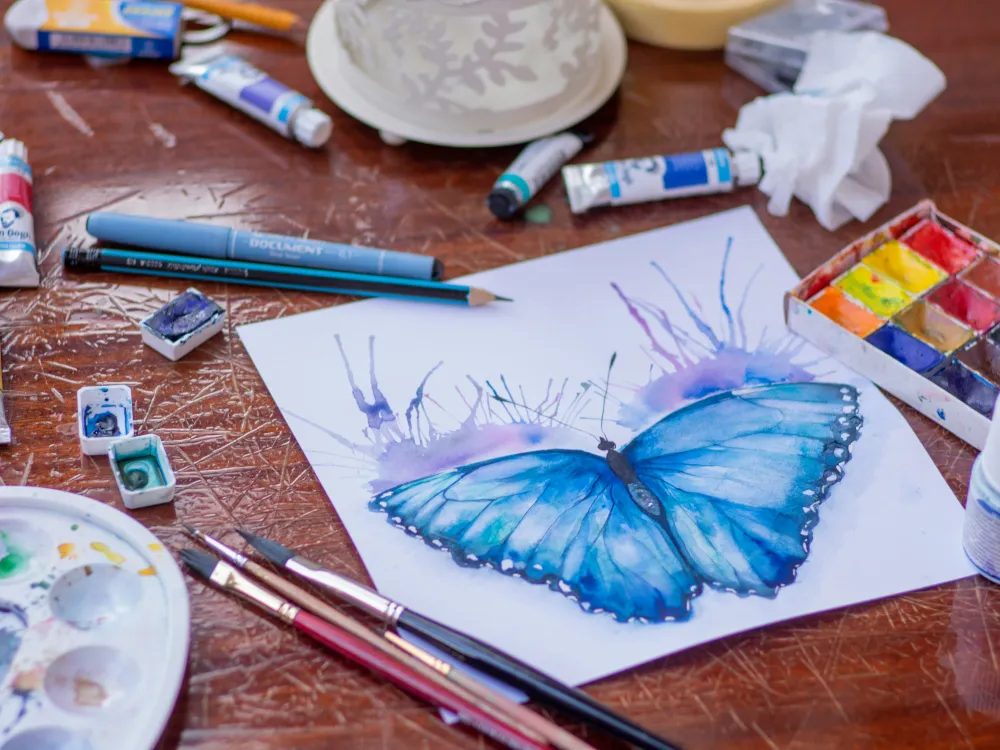 Materiales de arteterapia con una mariposa pintada en acuarela